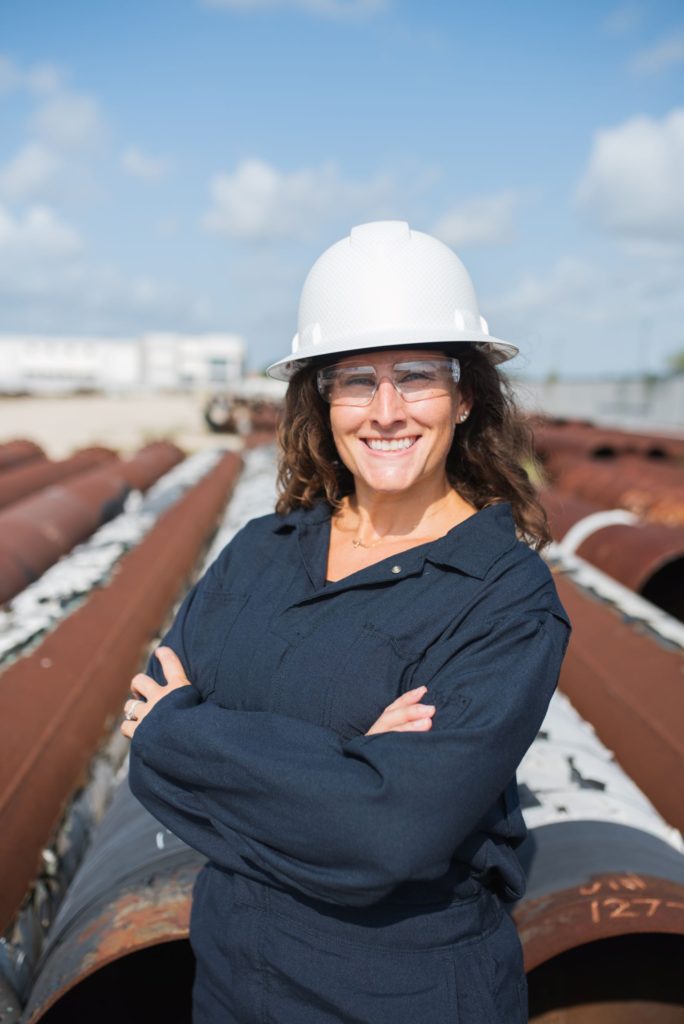 Cassandra smiling in PPE in front of pipe.